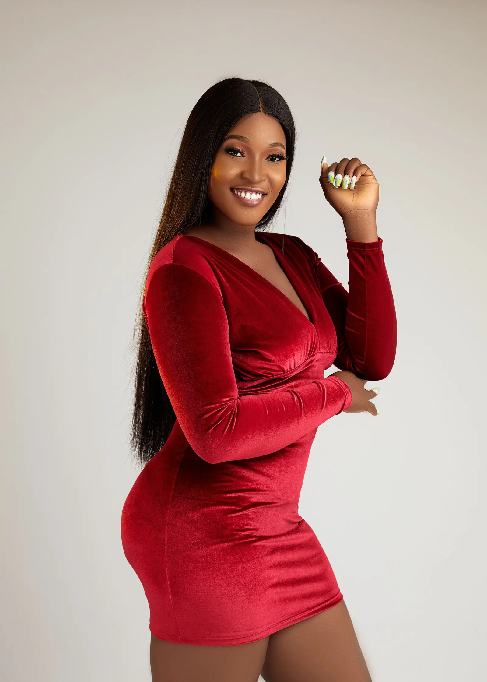 Smiling woman with long hair in a fitted red velvet dress