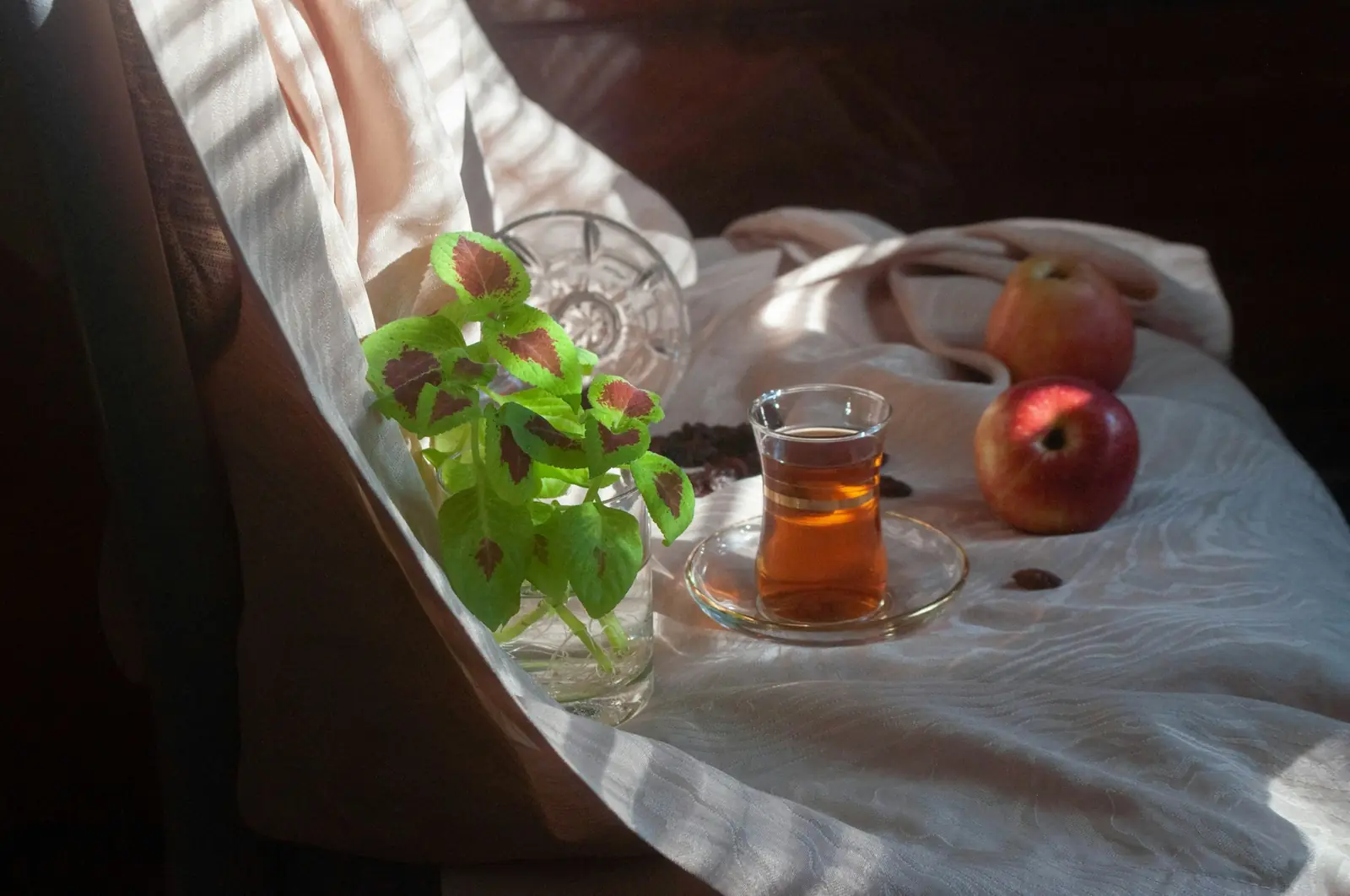 Glass of tea and fresh fruit on sunlit white linen